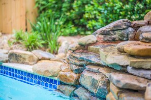 Ein Pool mit blau gefliestem Rand und einem Felsen.