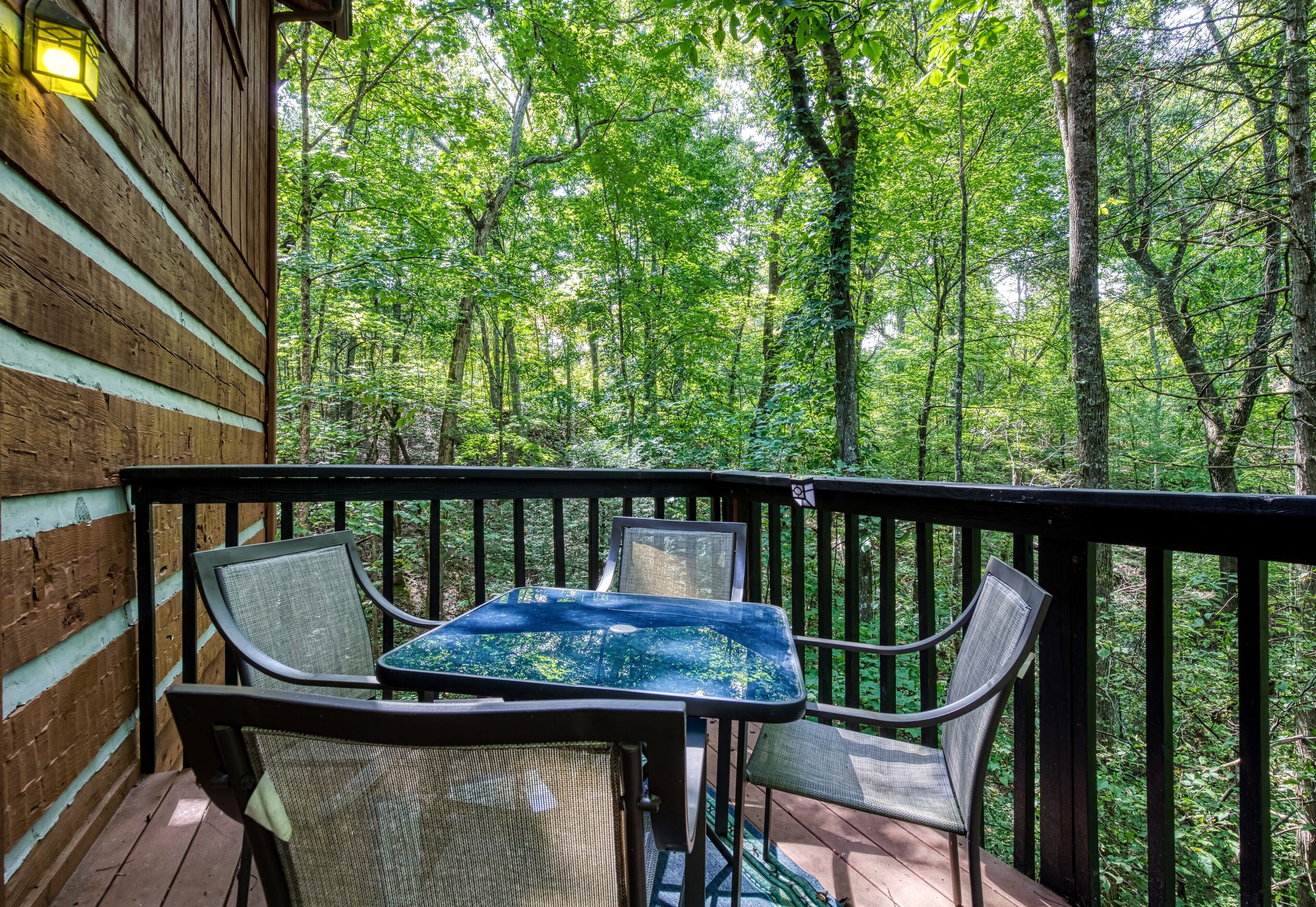 A wooden deck with a table and chairs overlooking a forest.