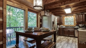Cocina de cabaña de madera con una isla grande, armarios de madera y vistas al bosque.