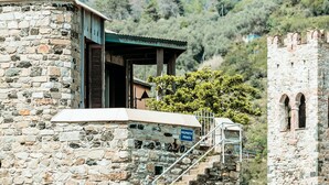 Un edificio de piedra con un balcón de madera, un letrero que indica propiedad privada y una escalera que conduce a una torre.