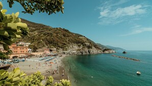 Una playa costera con aguas transparentes, un litoral rocoso y edificios a lo largo de la orilla.