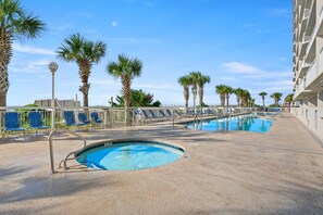 Relax by the pool surrounded by palm trees and lounge chairs.