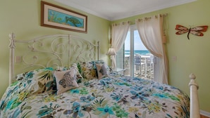 Ein Schlafzimmer mit einem Bett, einem Bild einer Meeresschildkröte, einer Schmetterlingsdekoration und Blick aufs Meer.