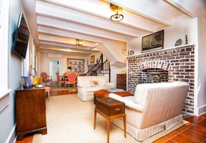 A cozy living room with a fireplace, a sofa, a coffee table, and a TV mounted on the wall.