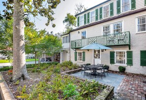 A two-story building with a balcony, outdoor seating, and a garden area.