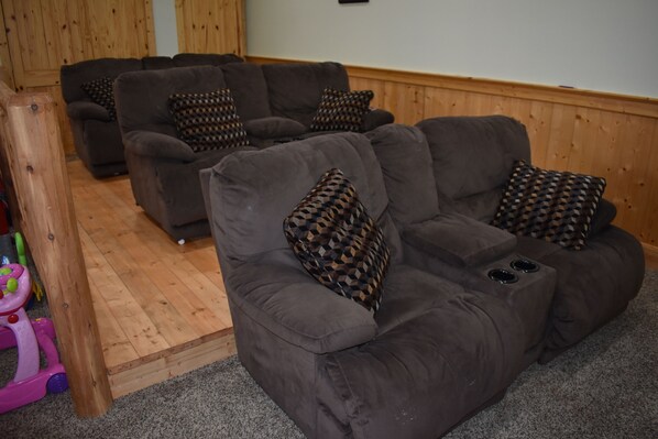 A living room with two grey sofas, each with patterned cushions, and a wooden floor. - Pool in back! -2x King Suites -120in Projection -Pool Table -HotTub -Easy Access (Pigeon Forge)
