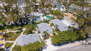 An aerial view of a resort with multiple buildings, a pool, and surrounding greenery.