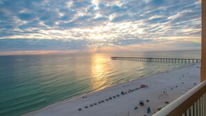 A beach with a pier extending into the sea, a sandy shore, and a few umbrellas and beach chairs. - L👀K!!! ⭐️ TOP RATED ⭐️ DIRECT BEACHFRONT Condo at Calypso + FREE Beach Chairs !!! (Panama City Beach)