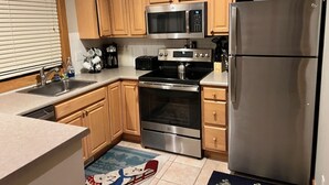 Une cuisine dotée de meubles en bois, d’appareils électroménagers en acier inoxydable, d’un four à micro-ondes, d’un four et d’un réfrigérateur.