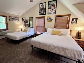 A bedroom with two beds, a window with blinds, and wall decorations.