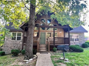 A lodge with a stone facade, wooden deck, and a green door.