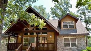 A lodge with a stone facade, wooden deck, and a sign indicating it is a lodge.