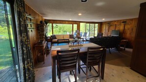 A cozy cabin interior with a dining area, a sofa, and a TV. - River Ranch Rental - Cabin in the woods--fishing, relaxation, wildlife, river (Irons)