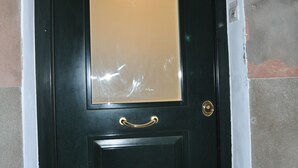 Una porta negra amb nansa daurada i un panell de vidre.