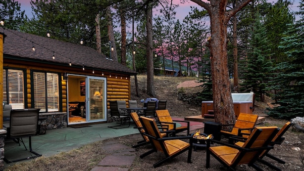 Eine Holzblockhütte mit einer Terrasse, die Gartenmöbel und eine Feuerstelle bietet.