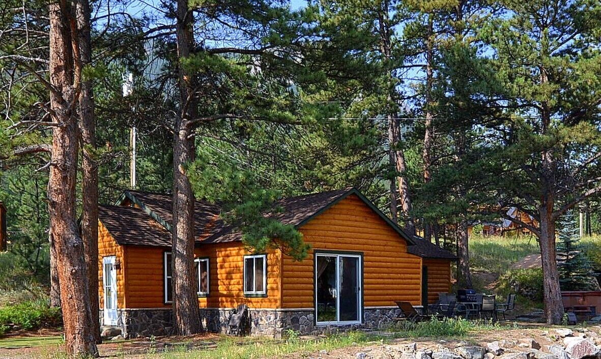 Une cabane en rondins avec des fondations en pierre, de grandes fenêtres et une porte.