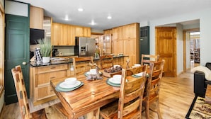 Eine moderne Küche mit Holzschränken, einem Edelstahlkühlschrank und einem Essbereich mit Holztisch und -stühlen.