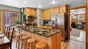 Eine moderne Küche mit Holzausstattung, Edelstahlgeräten und einer zentralen Kochinsel mit Barhocker.