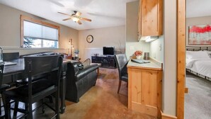 A compact living space with a dining area, a television, a clock, and a bed.