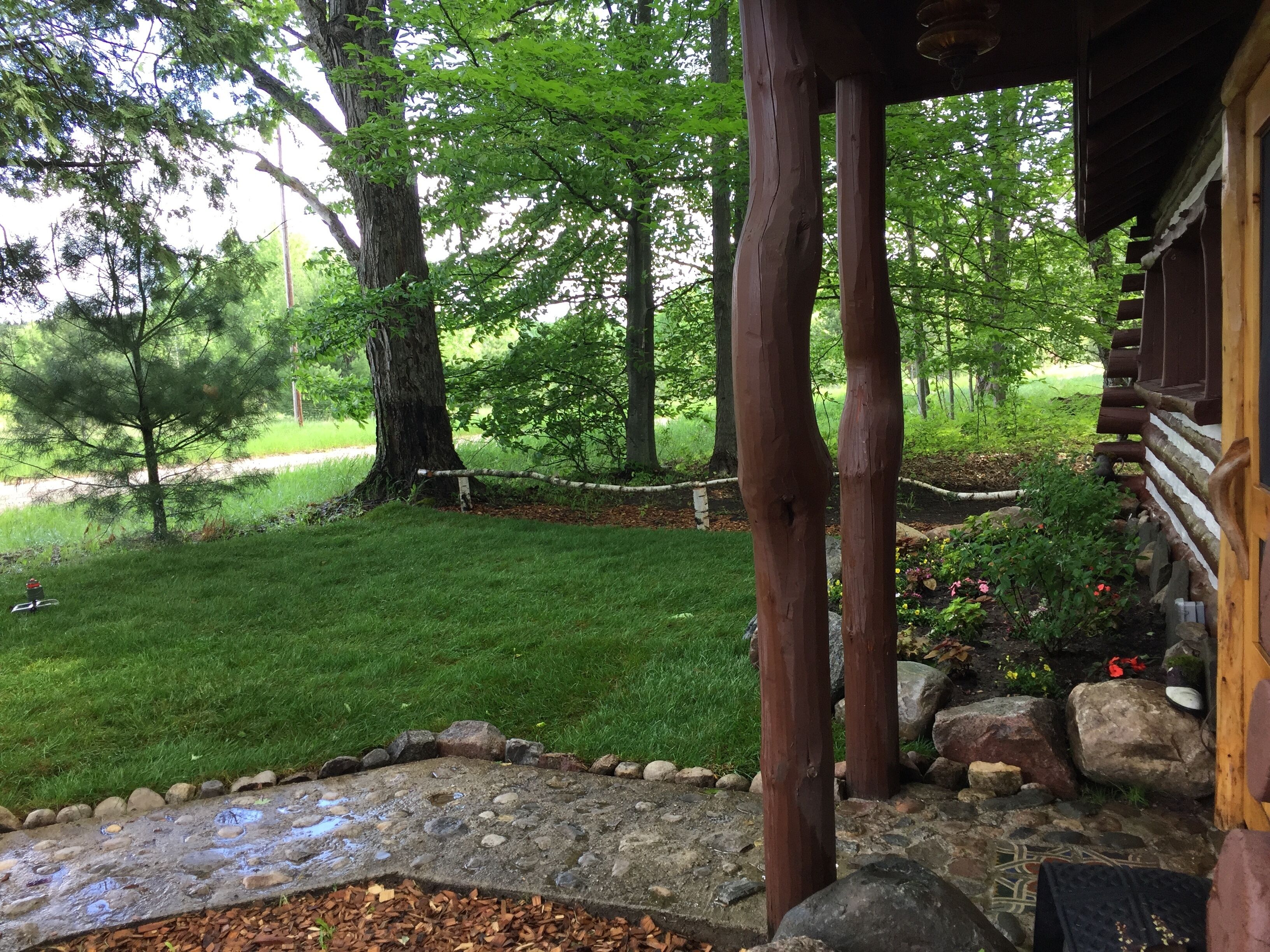 A wooden cabin with a stone pathway leading to a grassy area.