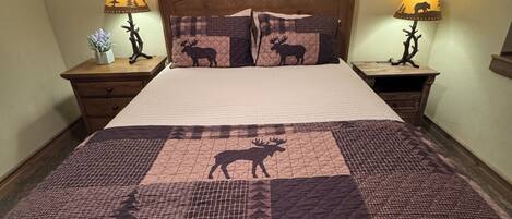A bed with a patterned quilt, two bedside lamps, and a wooden headboard.