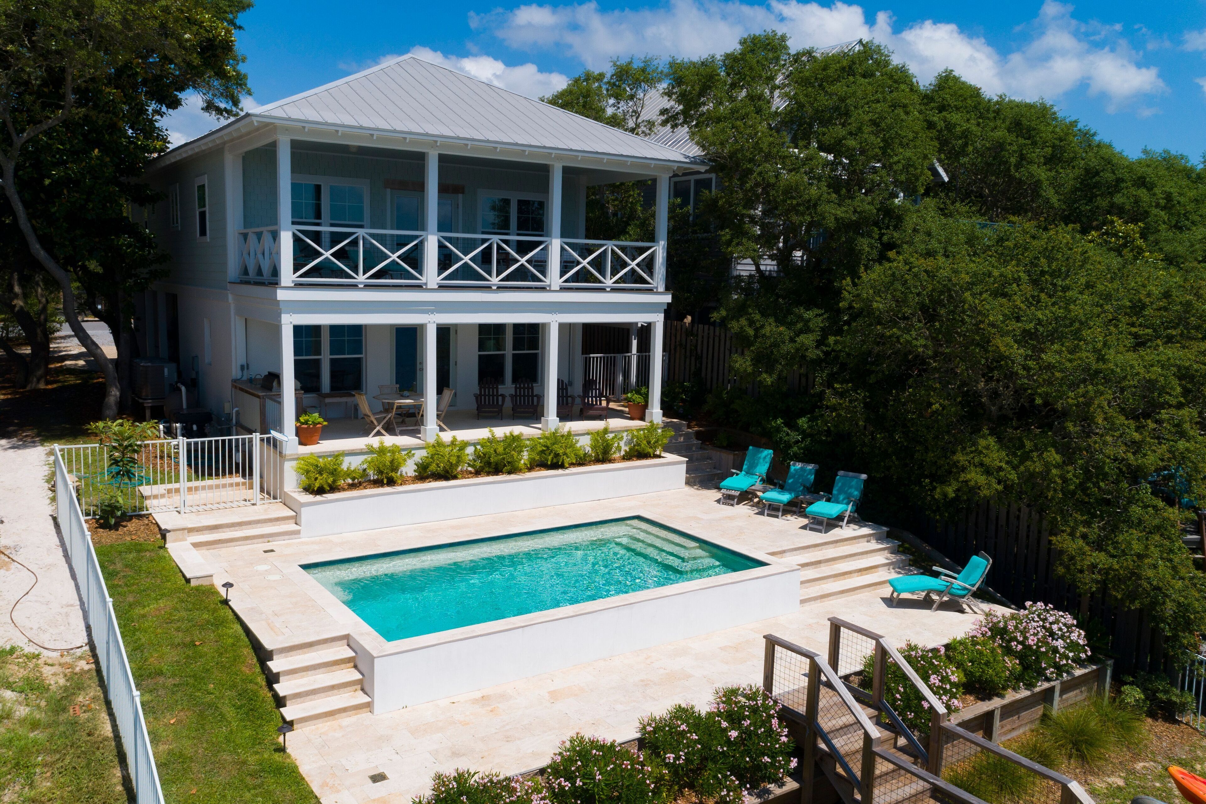 A two-story house with a pool, outdoor seating, and a fenced yard.