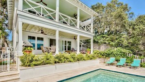 Une maison à deux étages dotée d’une piscine, d’un espace salon extérieur et d’un patio couvert.