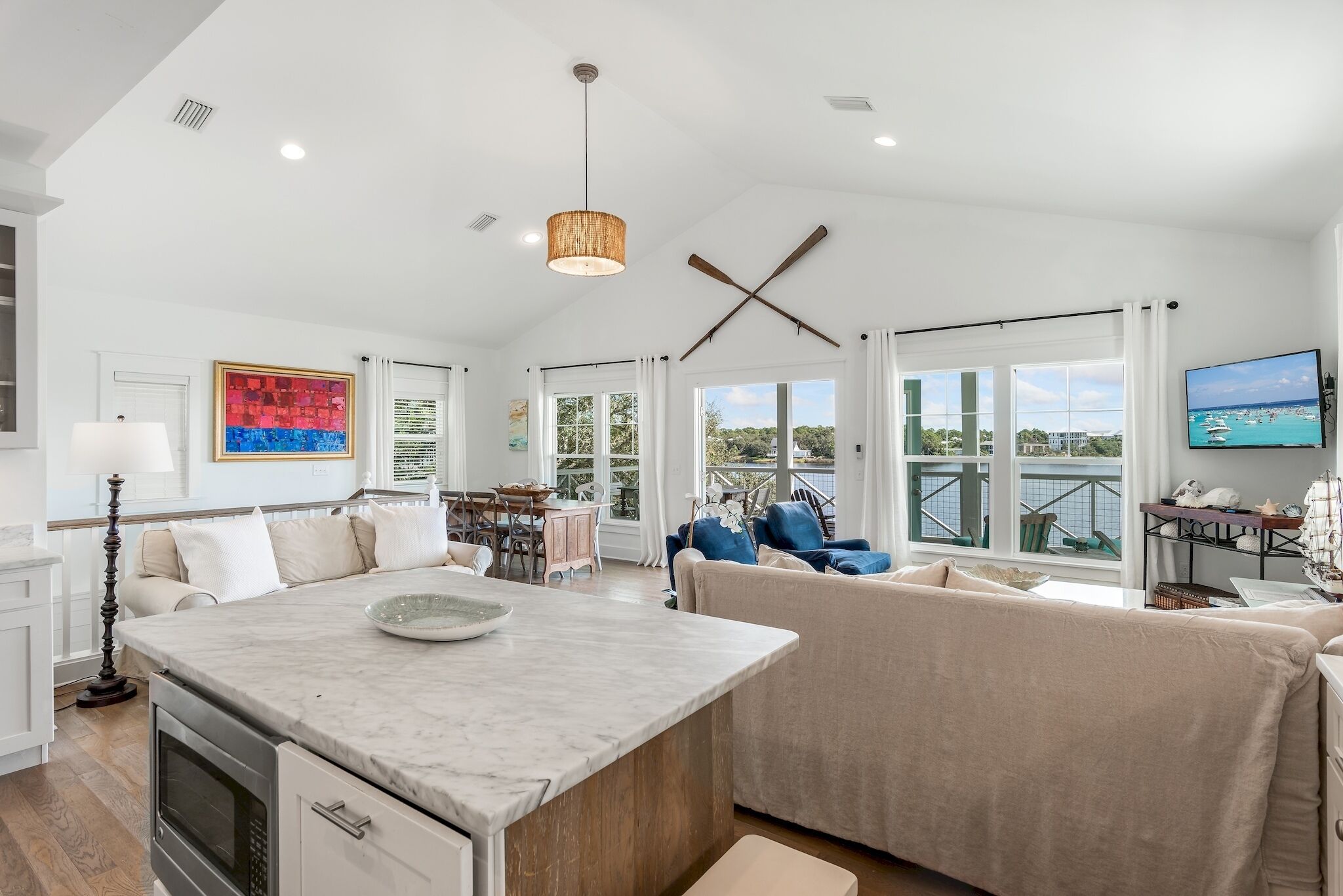 A spacious living area with a large window, a kitchen island, and a dining area.