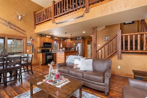 A spacious living area with a high ceiling, wooden staircase, and a kitchen with modern appliances. - Cash`s Sluice - Access to Pool! (Lead)