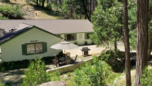 A lodge with a patio area featuring outdoor furniture and a grill. - Beautiful Creekside Home in Mariposa Pines Close to Yosemite.  No cleaning fee.  (Mariposa)
