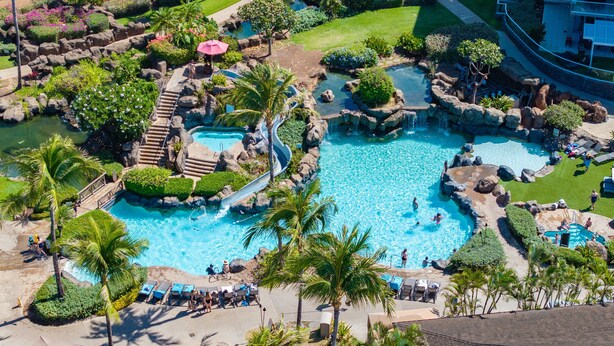 An aerial view of a resort with multiple swimming pools, a waterfall, and a variety of tropical plants. - Oceanfront Views Above Dukes - Wrap Around Lanai - Outdoor Kitchen 🌺 Honua Kai H351 (Lahaina)