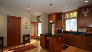 Eine moderne Küche mit Holzausbau, einem Edelstahlkühlschrank und einer schwarzen Arbeitsplatte.