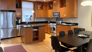 Eine moderne Küche mit Holzschränken, Edelstahlgeräten und einer Essecke mit Tisch und Stühlen.