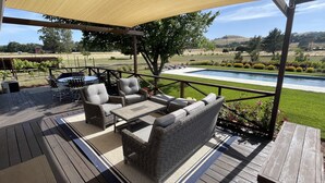 Un patio al aire libre con mobiliario de mimbre, una piscina y vistas al campo.
