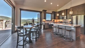 Una cocina moderna con una isla grande, piso de madera oscura y vistas al exterior.