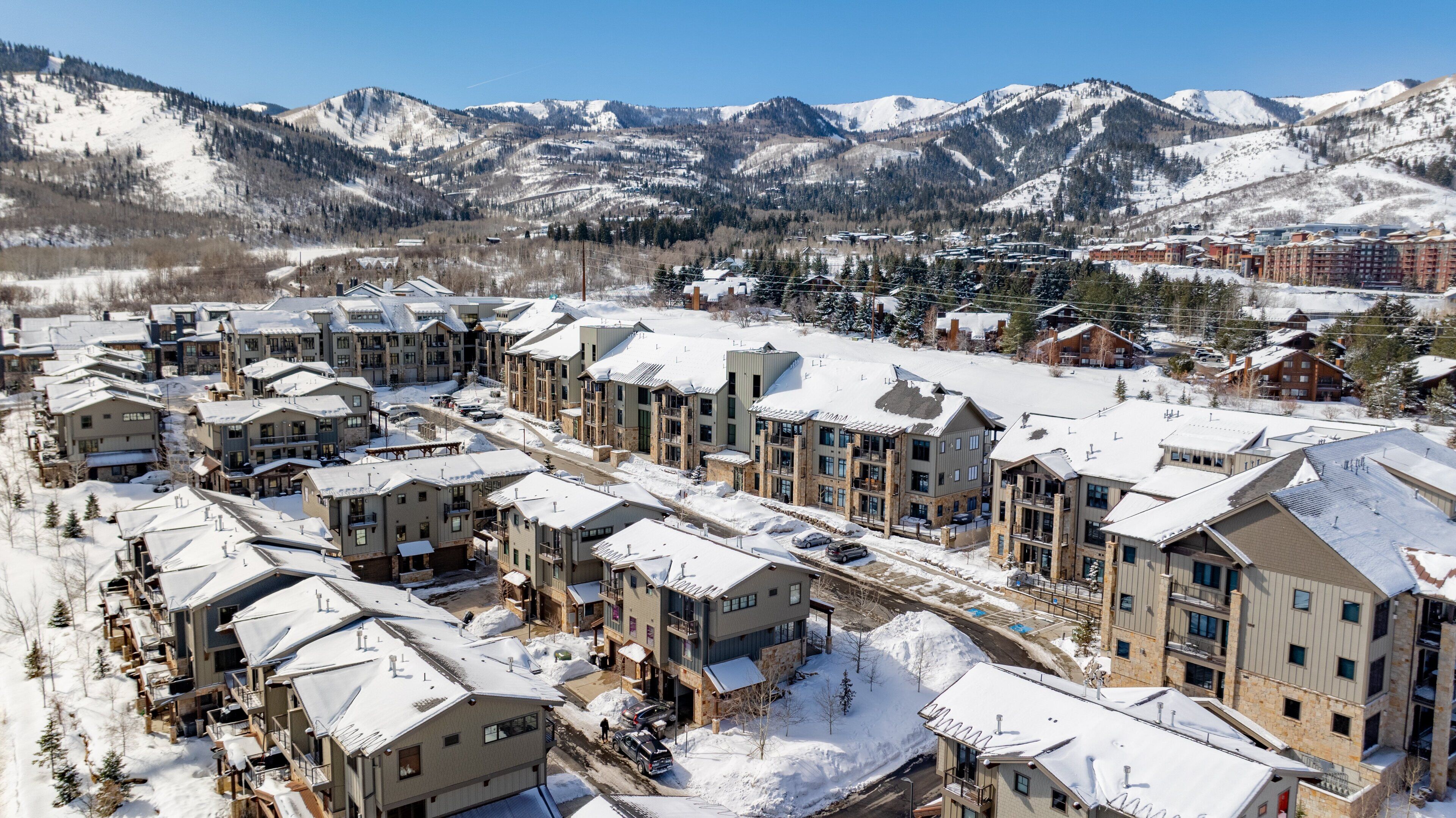 Un complejo turístico cubierto de nieve con varios edificios, incluyendo un hotel con balcones y una cabaña para esquiar.