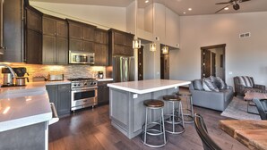 Una cocina moderna con armarios de madera oscura, electrodomésticos de acero inoxidable y una isla central con taburetes.
