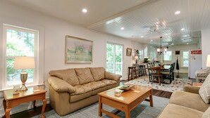 A spacious living room with a beige sofa, a wooden coffee table, and a dining area with a table and chairs. - Charming 125 Year Old Sewanee Home on Campus- Walk Everywhere! (Sewanee)