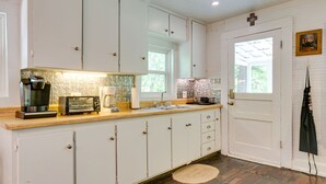A kitchen with white cabinets, a wooden countertop, a coffee maker, a toaster, and a sink. - Charming 125 Year Old Sewanee Home on Campus- Walk Everywhere! (Sewanee)