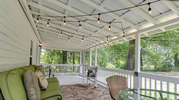 A covered porch with a green cushioned sofa, a wicker chair, and a glass table. - Charming 125 Year Old Sewanee Home on Campus- Walk Everywhere! (Sewanee)