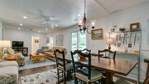 A spacious living room with a wooden dining table, dark wooden chairs, a chandelier, and a television in the background. - Charming 125 Year Old Sewanee Home on Campus- Walk Everywhere! (Sewanee)