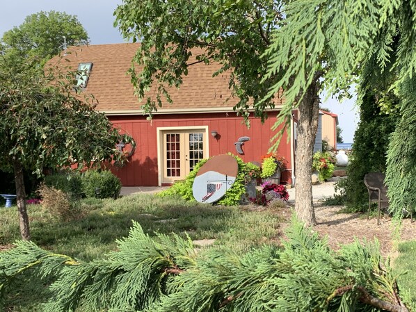 Una casa roja con techo marrón, rodeada de vegetación y un jardín.