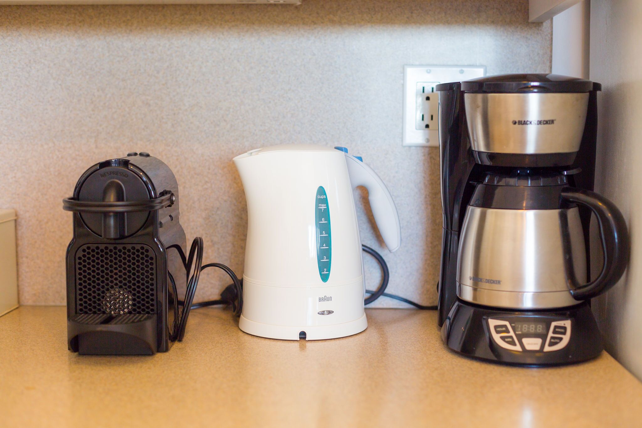 Una encimera de cocina con cafetera, hervidor y molinillo de café.