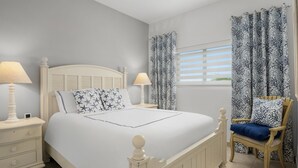 A bedroom with a bed, nightstands, a chair, and curtains. - Updated Stunning Ocean Club Plaza luxury family spacious top floor apartment  (Providenciales)