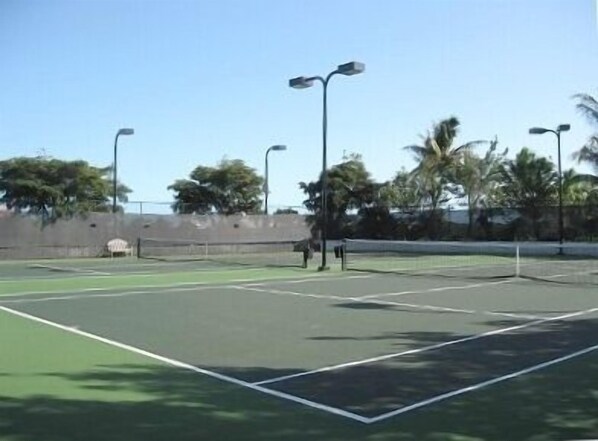 Una cancha de tenis con superficie de juego verde y líneas divisorias blancas.