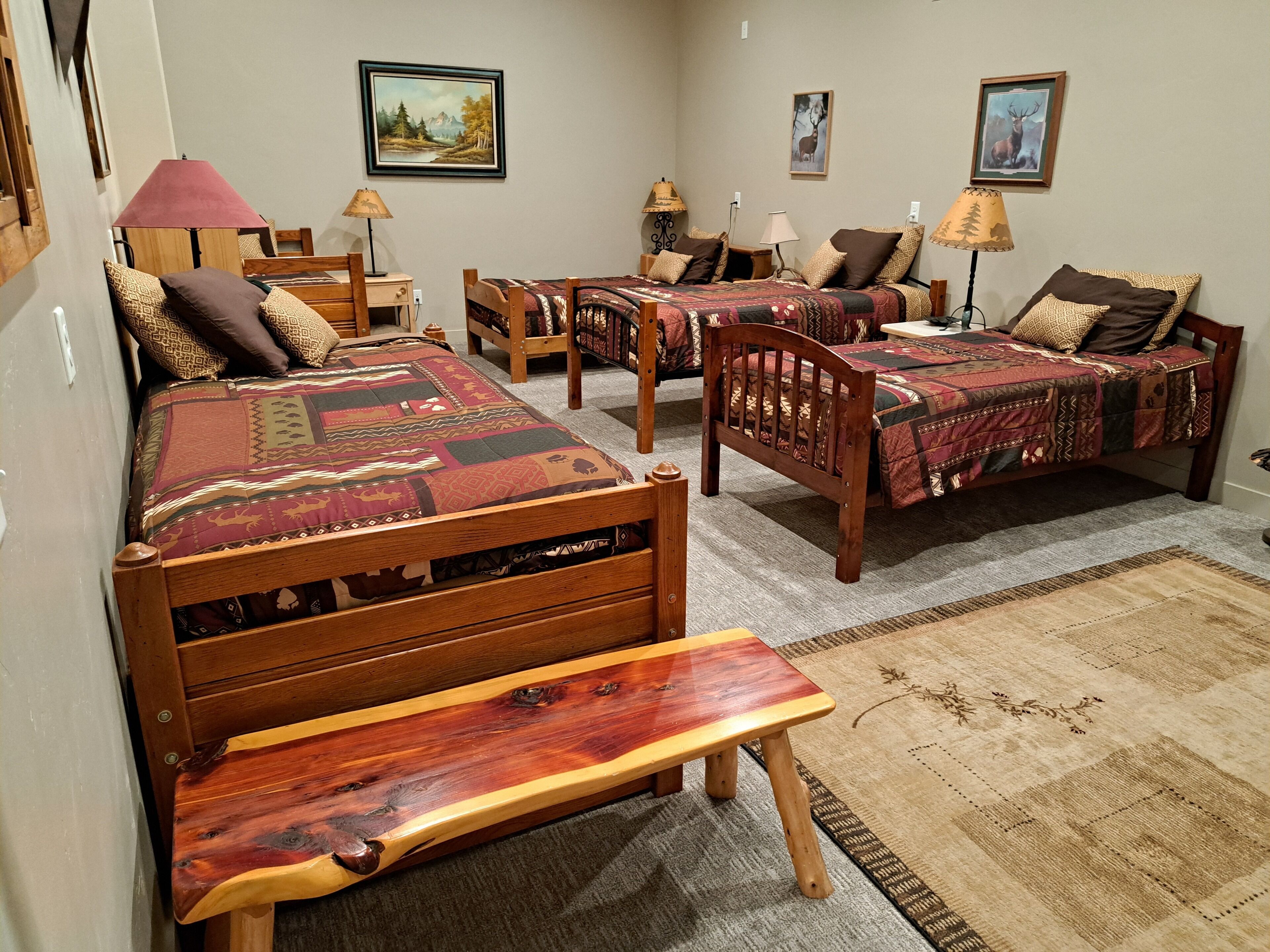 A room with two wooden beds, a wooden bench, a small table, and a rug.
