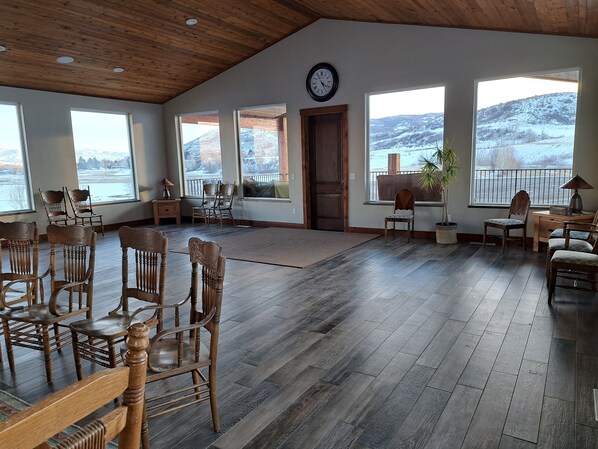 A spacious room with wooden flooring, large windows offering views of a snowy landscape, and several wooden chairs and tables. - One of a kind Mountain Lodge 10,000 sq ft sleeps 51. Perfect Year Round location (Morgan)