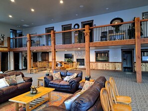 A spacious lobby with a high ceiling, wooden beams, a fireplace, and a second-floor balcony with railings. - One of a kind Mountain Lodge 10,000 sq ft sleeps 51. Perfect Year Round location (Morgan)