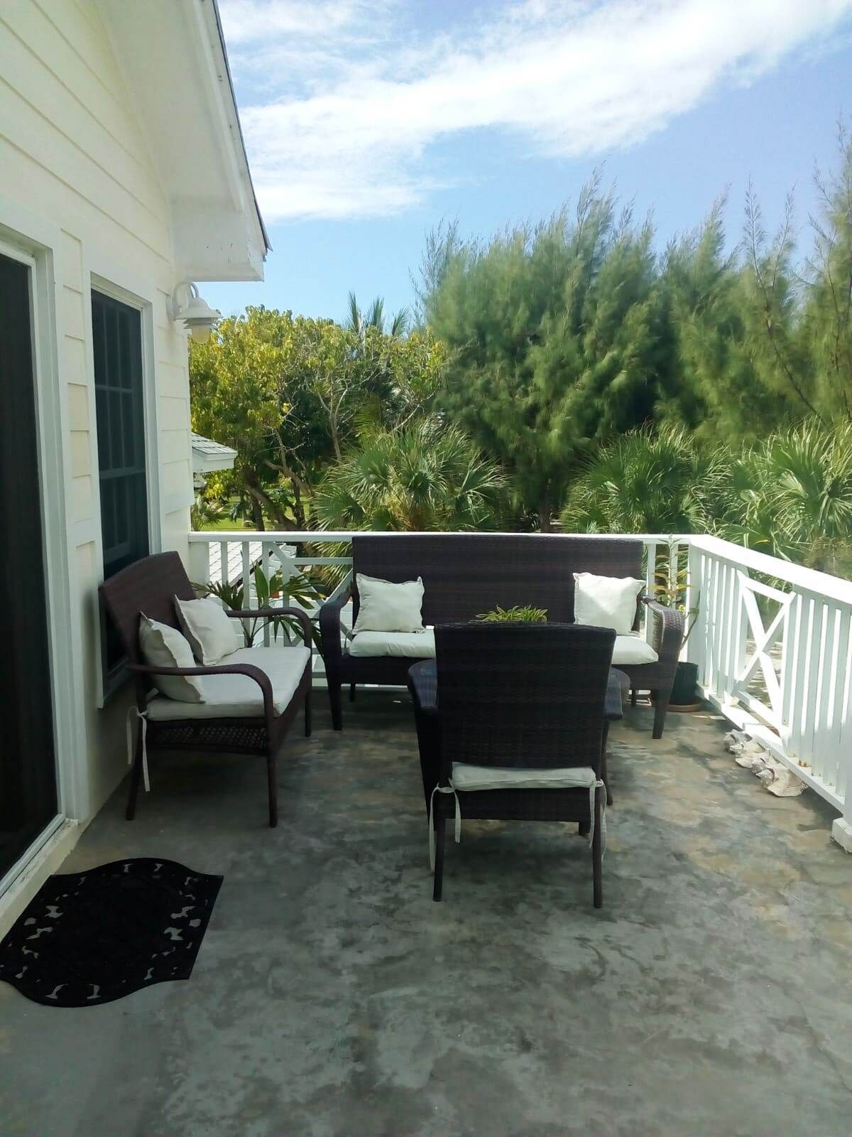 A covered outdoor seating area with two chairs and a table, surrounded by a white railing.