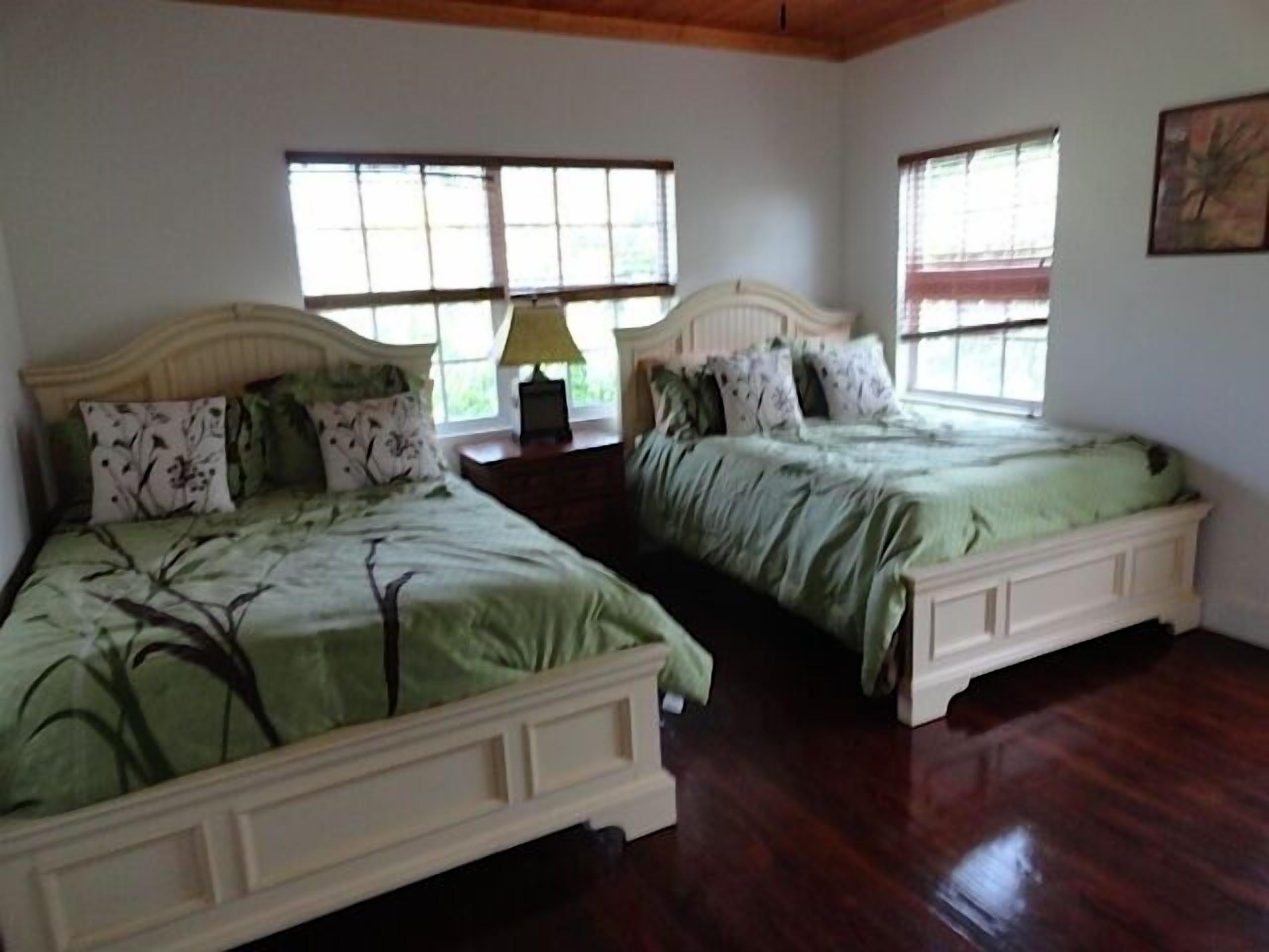 A bedroom with two beds, a nightstand, and a window.
